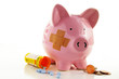 Bandaged piggy bank with pills and coins Bandaged piggy bank with pills and coins