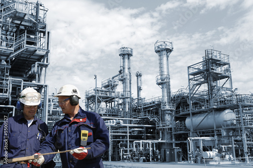 Photo: engineers and large oil refinery in blue engineers and large oil refinery in blue
