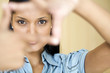 Businesswoman looking through frame made with her fingers