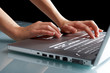 Hands typing on a laptop