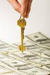 Hand holding a golden key over dollar background Hand holding a golden key over dollar background