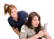 Sister/friend looking over shoulder shocked at cellphone