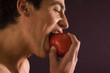 Young man eating red apple