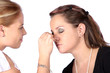Makeup artist applying finishing touches to model