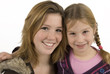 two cute sisters embracing against white background