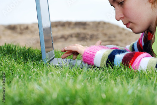 Photo: young girl is working on laptop at outdoor location young girl is working on laptop at outdoor location