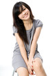 Foto: A cute young Asian teenager in grey dress on white background A cute young Asian teenager in grey dress on white background