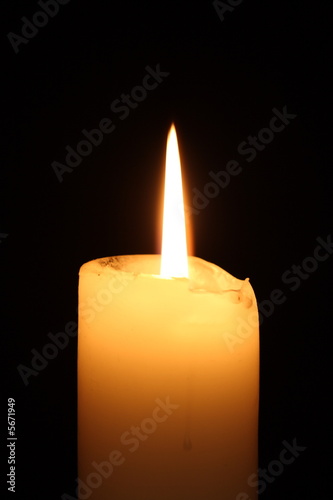 Photo: Lit candle on black background Lit candle on black background