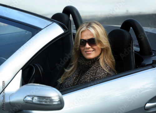 Photo: Blond girl in sunglasses driving convertable car Blond girl in sunglasses driving convertable car
