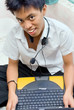 Smiling Asian schoolboy in his room with laptop Smiling Asian schoolboy in his room with laptop