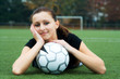 A beautiful soccer player resting on a soccer ball