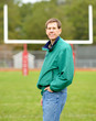 A man standing on a football field with the goalpost behind him.