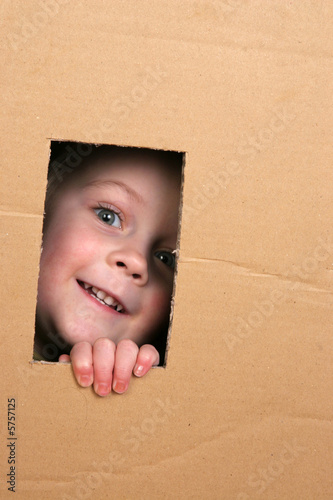 young girl looking from brown carton box