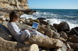 girl on the rocks near the sea relaxing and using a laptop girl on the rocks near the sea relaxing and using a laptop
