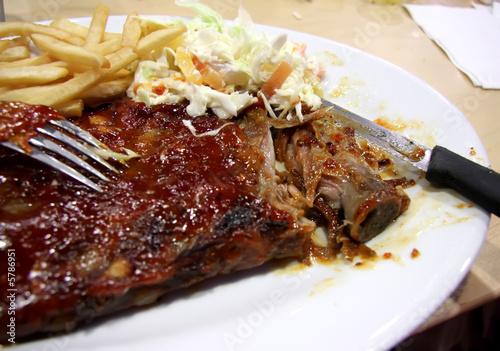 Barbecued babyback ribs with sauce on plate with fries