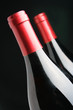 Two corked wine bottles over black background