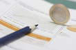 Euro coin on edge, pencil and stock market graph