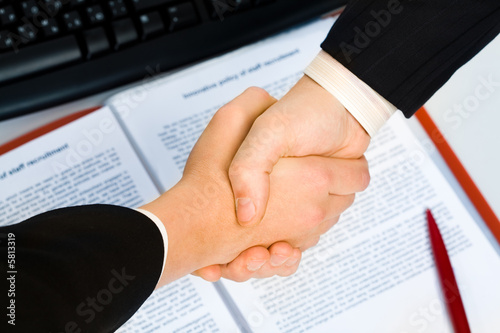 View of handshake over contract with pen in the background