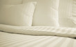 Bed with set of crisp striped sheets and pillows