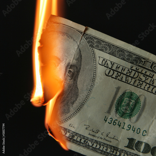 Photo: Burning dollars close up over black background Burning dollars close up over black background