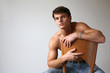 Sexy muscular man sitting on the wooden chair. Copy space
