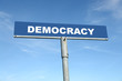 Metal signpost spelling Democracy over blue sky
