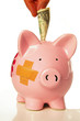Hand putting a dollar into a bandaged piggy bank Hand putting a dollar into a bandaged piggy bank