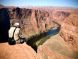 An eldery man hangs his legs off a cliff to get a picture