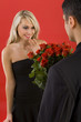 Young man in suit is giving flowers to  woman