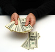 Photo: man spreading out stack of money with some on table man spreading out stack of money with some on table