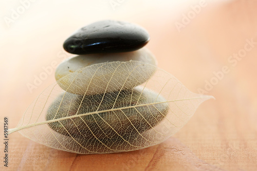 Photo: Stacked stones and skeleton leaf on warm wood background Stacked stones and skeleton leaf on warm wood background