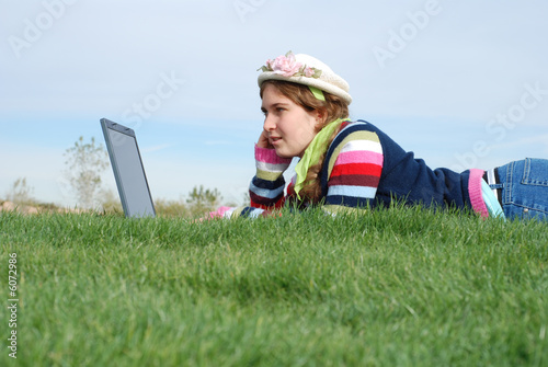 Photo: young girl is working on laptop at outdoor location young girl is working on laptop at outdoor location