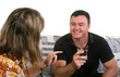 Middle aged adults chatting on a sofa with the man laughing.