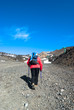 Hiker with poles walking the stony trail on the volcano Etna