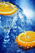 Two slices of orange and a glass in blue clean water
