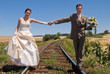 Bride and groom holding hands and balancing on rails