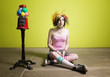 Photo : Colorful young punk girl sitting in front of a green wall Colorful young punk girl sitting in front of a green wall