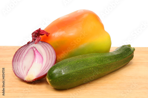 Photo: onion,corgette and pepper on wooden board onion,corgette and pepper on wooden board