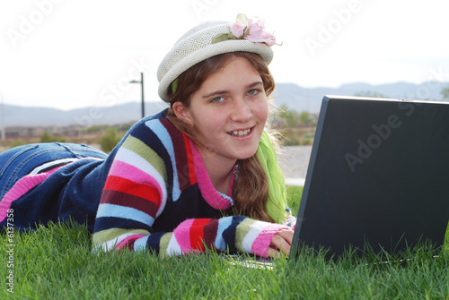 Photo: young girl is working on laptop at outdoor location young girl is working on laptop at outdoor location