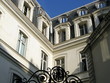 Coin de façade blanche au dessus d'une porte en fer forgée.