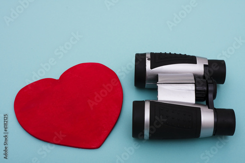 Photo: Heart shape with binoculars on blue background Heart shape with binoculars on blue background