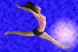 a cute gymnast in a hard jump on a blue background