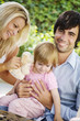 young family sitting in the garden in the summer time