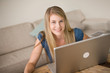 A blonde girl at home using a laptop computer