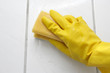 Hand in yellow glove with sponge, washing bathroom's wall