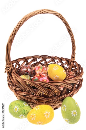 Photo: The wooden basket filled with Easter eggs - isolated on white The wooden basket filled with Easter eggs - isolated on white