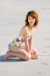 woman in swimsuit kneeling by the beach