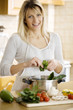  female putting a bunch of healthy ingredients in a cooking pan