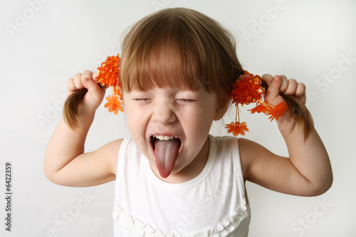 Photo: Little girl sticking out her tongue at the camera for fun Little girl sticking out her tongue at the camera for fun
