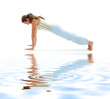 sporty girl practicing four-limbed staff pose on white sand